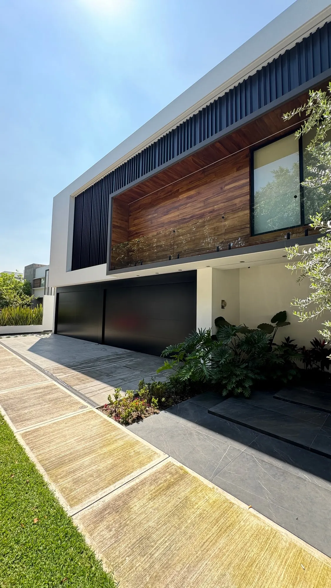 Portón ascendente en fachada contemporánea con celosía de madera