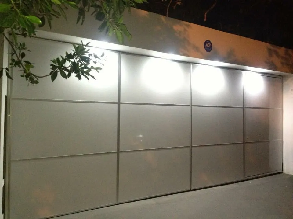 Portón plegadizo con vidrio esmerilado e iluminación nocturna