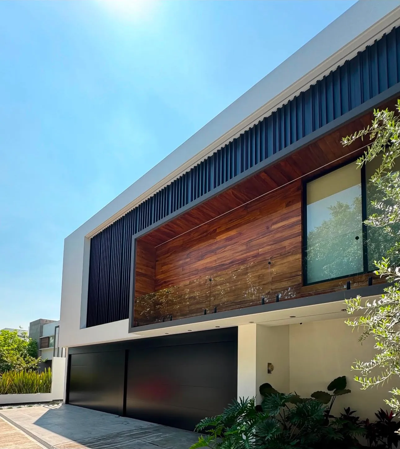 Residencia contemporánea con portones automáticos Portalum en negro mate, fachada de madera y celosía metálica